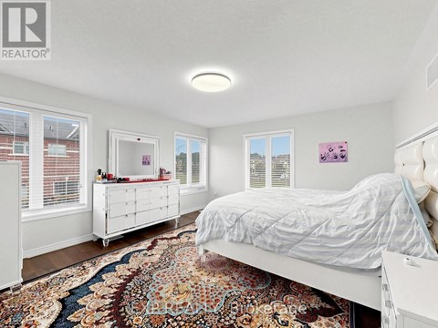 A bedroom with a large bed and a rug on the floor.
