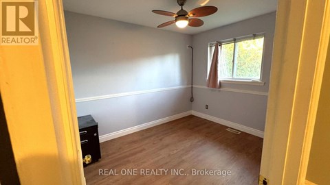 A room with a ceiling fan and a window with a view of trees outside.