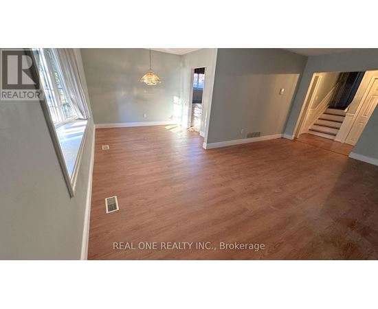 A spacious room with wooden flooring and a chandelier hanging from the ceiling.