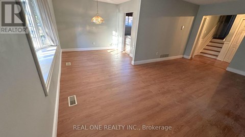 A spacious room with wooden flooring and a chandelier hanging from the ceiling.