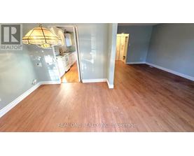 A room with wooden flooring and a Realty sign on the wall.