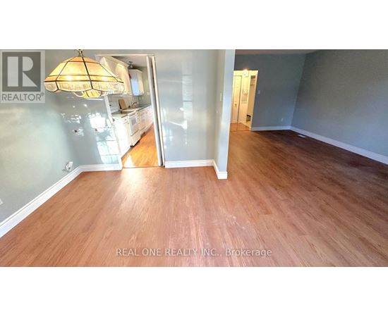 A room with wooden flooring and a Realty sign on the wall.