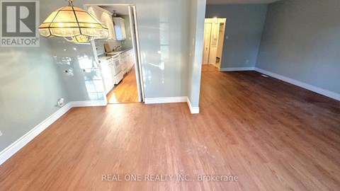 A room with wooden flooring and a Realty sign on the wall.