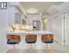 A modern kitchen with white cabinets and a bar area with two stools.