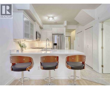 A modern kitchen with white cabinets and a bar area with two stools.