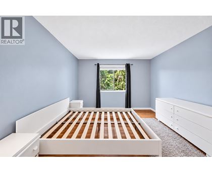A bedroom with a bed, dresser, and window.