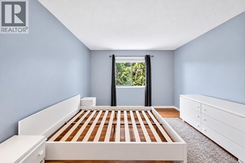 A bedroom with a bed, dresser, and window.