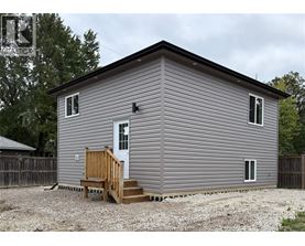 A grey house with a white door and a brown porch.