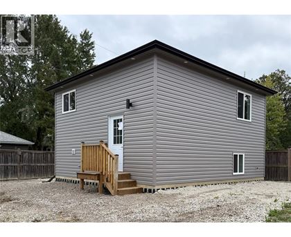 A grey house with a white door and a brown porch.