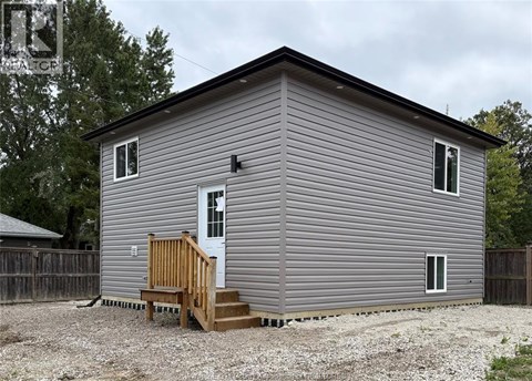 A grey house with a white door and a brown porch.