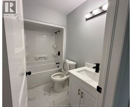 A white bathroom with a toilet, sink, and shower.