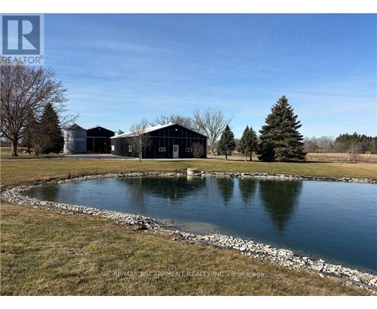 A pond in front of a building with the logo REALTOR on the top left.