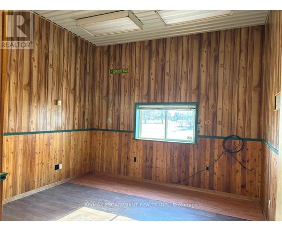 A room with wooden walls and a window showing trees outside.