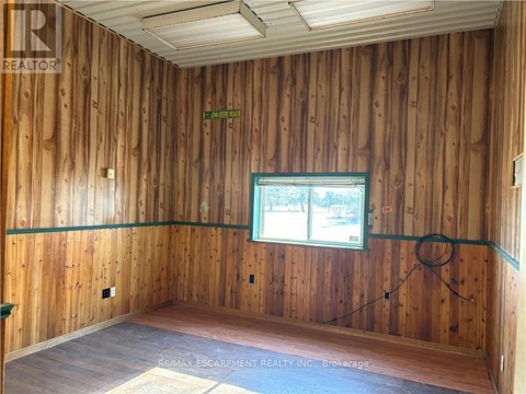 A room with wooden walls and a window showing trees outside.