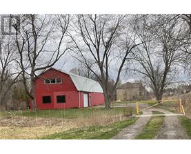 A red barn sits in a field with a yellow gate in front.