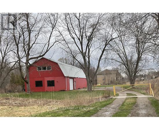 A red barn sits in a field with a yellow gate in front.