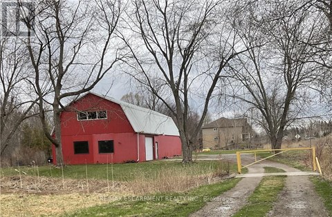 A red barn sits in a field with a yellow gate in front.