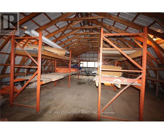 A large, empty attic space with wooden beams and a concrete floor.