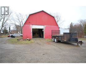 A red barn with a truck parked in front of it.