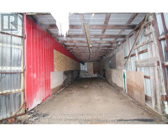 A long, narrow, red and white building with a lot of debris on the floor.