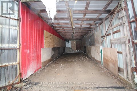 A long, narrow, red and white building with a lot of debris on the floor.