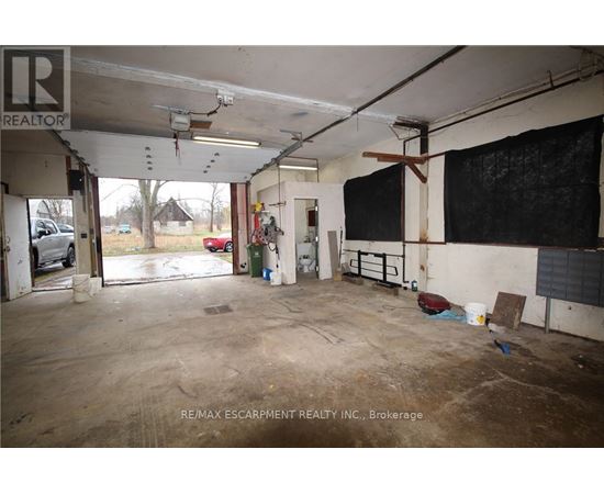 A large, empty warehouse space with a sign that reads "RE/MAX Escarpment Realty Inc., Brokerage.".