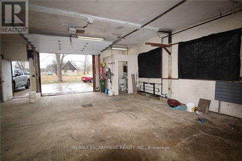 A large, empty warehouse space with a sign that reads "RE/MAX Escarpment Realty Inc., Brokerage.".