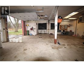 A large, empty garage with a lot of debris on the floor.