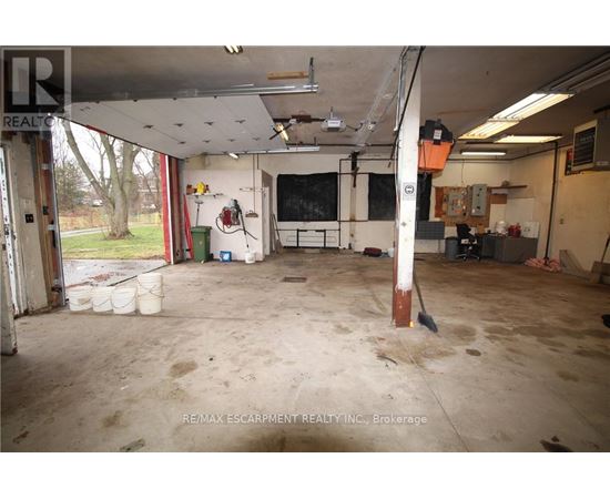 A large, empty garage with a lot of debris on the floor.
