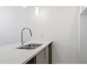 A modern kitchen with a white countertop and a stainless steel sink.