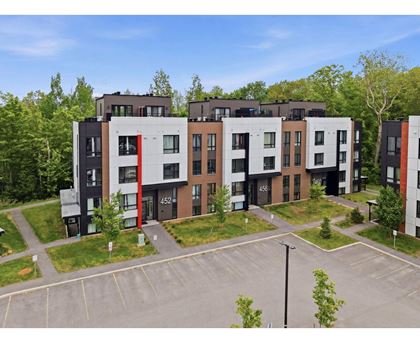 Apartment complex with a parking lot in front.