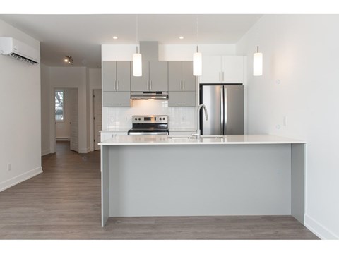 A modern kitchen with a refrigerator, stove, and cabinets.