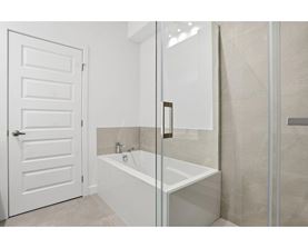 A white door is open to a bathroom with a glass shower door.