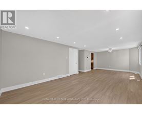 A spacious room with wooden flooring and white walls.