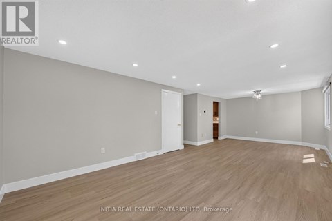 A spacious room with wooden flooring and white walls.