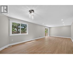 A room with wooden floors and a window showing trees outside.