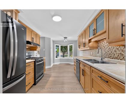 A kitchen with wooden cabinets and a black refrigerator.