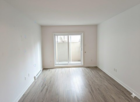 A room with a large window and wooden flooring.