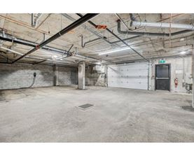 A large, empty industrial-style room with a concrete floor and exposed pipes on the ceiling.