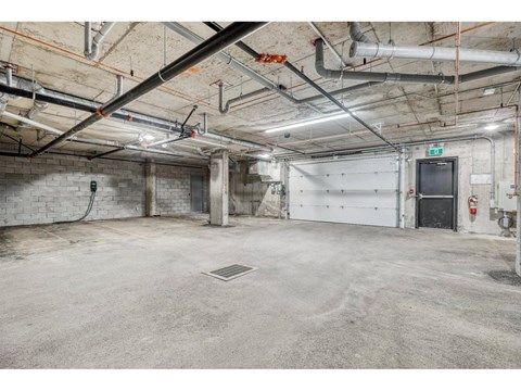A large, empty industrial-style room with a concrete floor and exposed pipes on the ceiling.