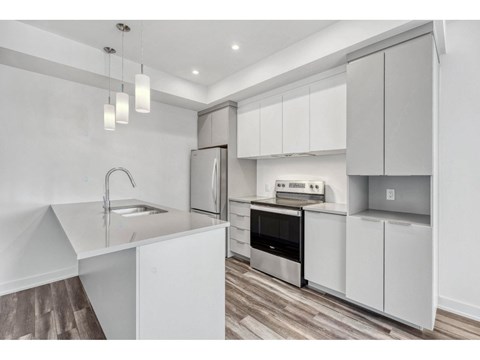 A modern kitchen with white cabinets and stainless steel appliances.