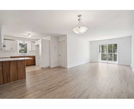 A spacious room with wooden flooring and white walls.