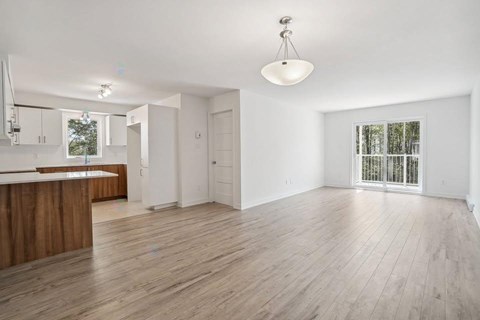 A spacious room with wooden flooring and white walls.