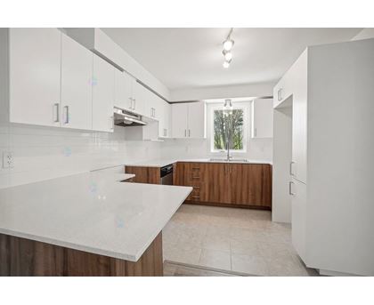 A kitchen with white cabinets and a white counter top.