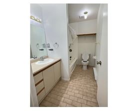 A bathroom with a toilet, sink, and mirror.