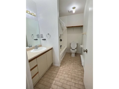 A bathroom with a toilet, sink, and mirror.