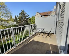 A white metal table and chairs are on a patio.