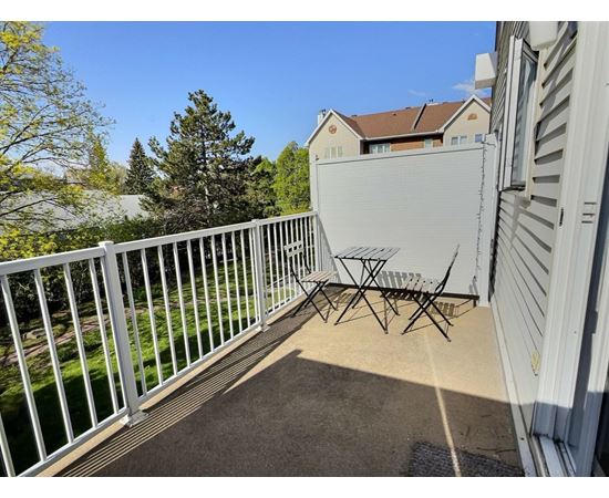 A white metal table and chairs are on a patio.