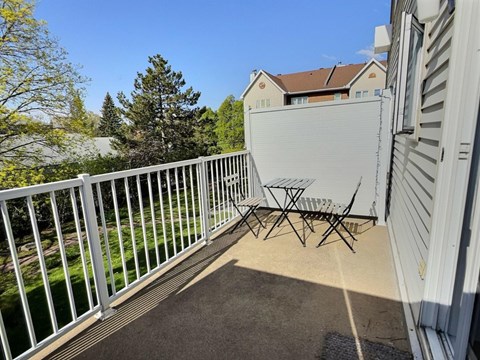 A white metal table and chairs are on a patio.