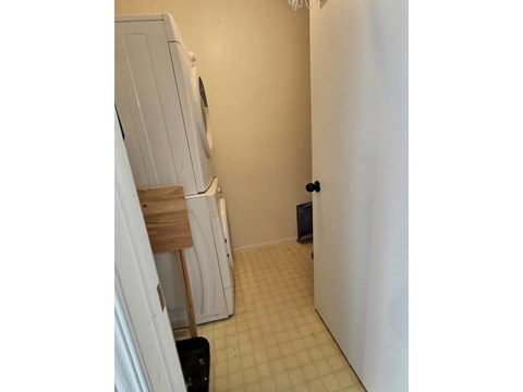 A white refrigerator is in a kitchen with a black trash can.